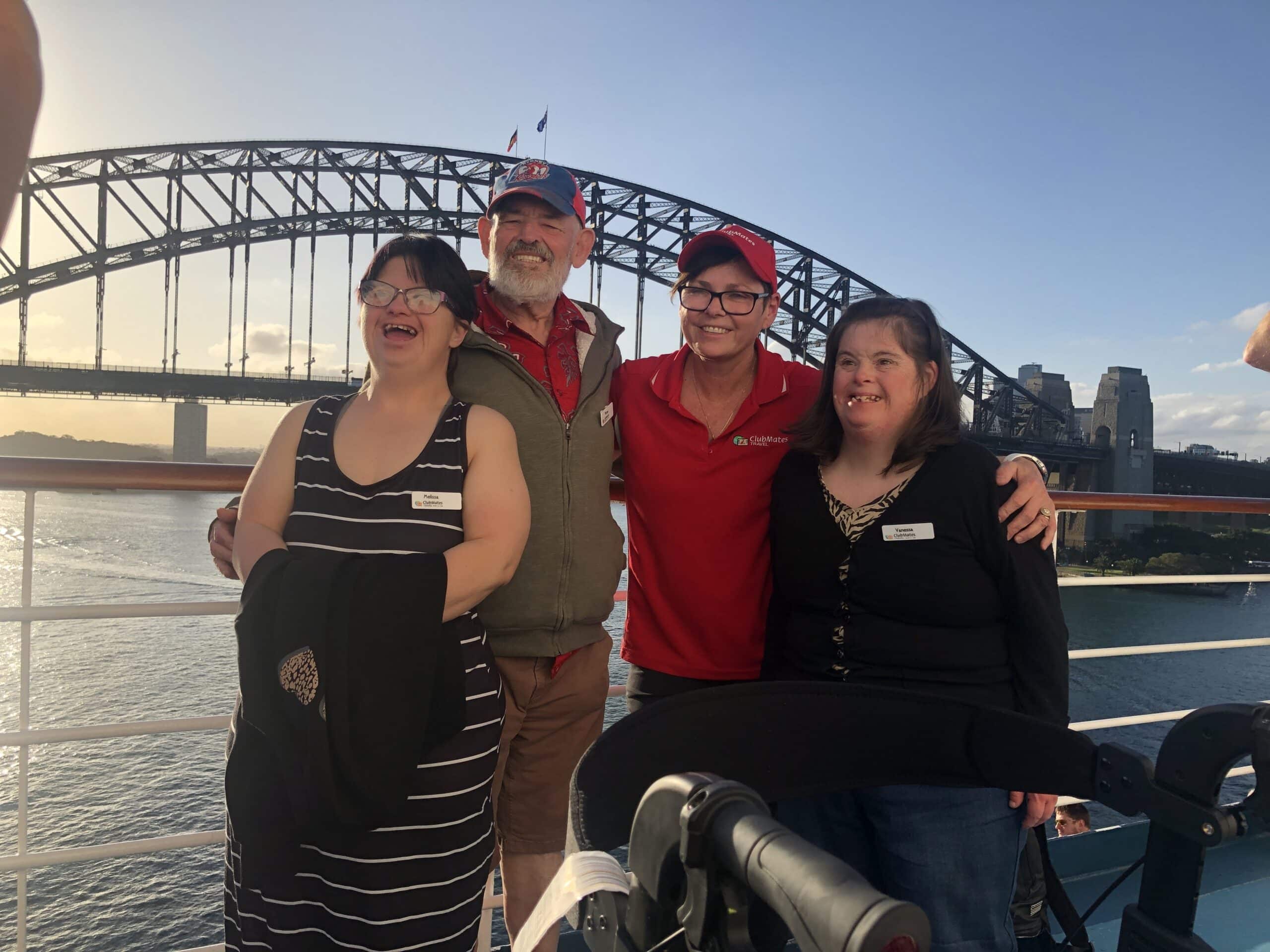 3 ClubMates passengers with their support worker looking happy in front of the Sydney Harbour Bridge